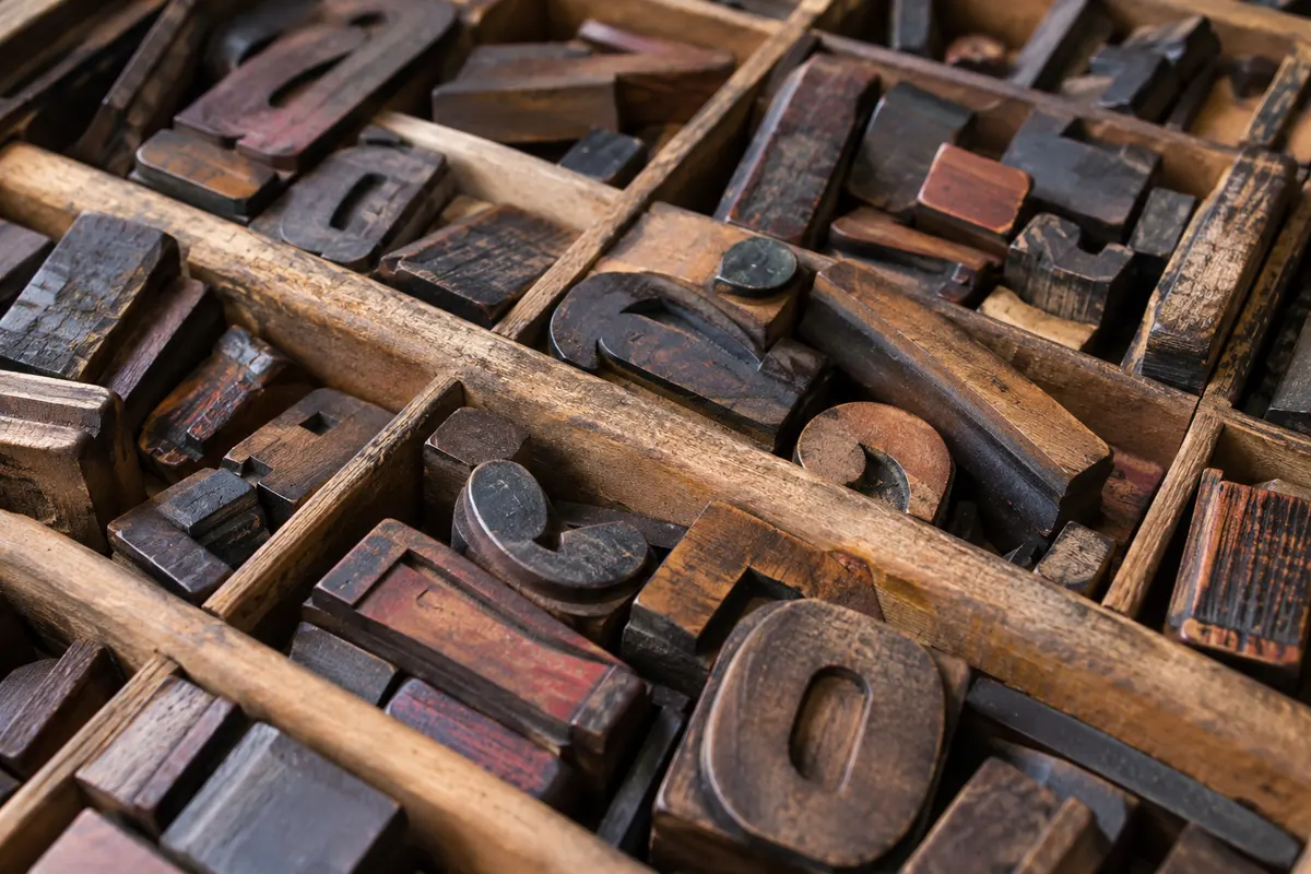 Ink-worn wooden letterpress type arranged in a printmaker’s tray