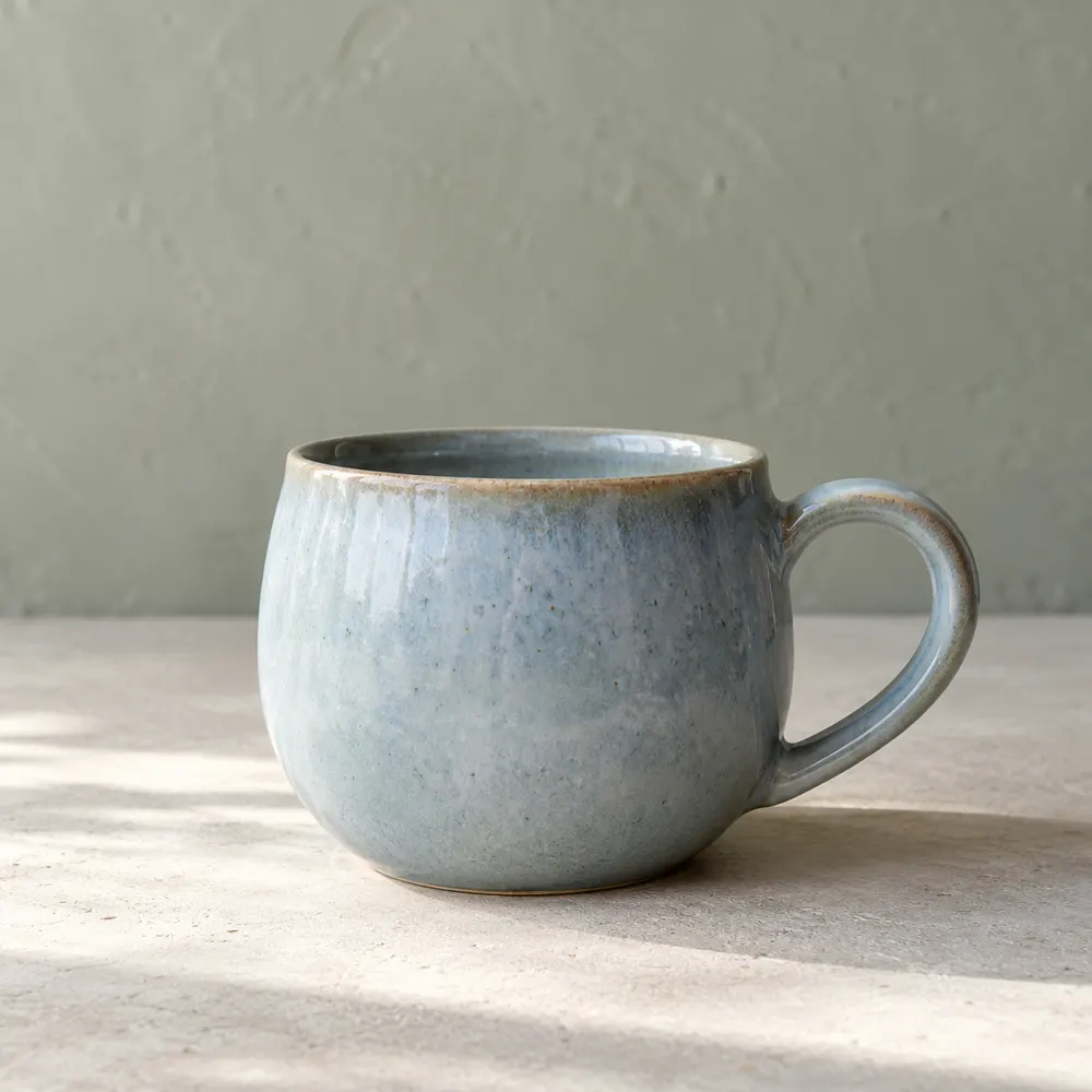 A cloud-blue ceramic cup in soft window light